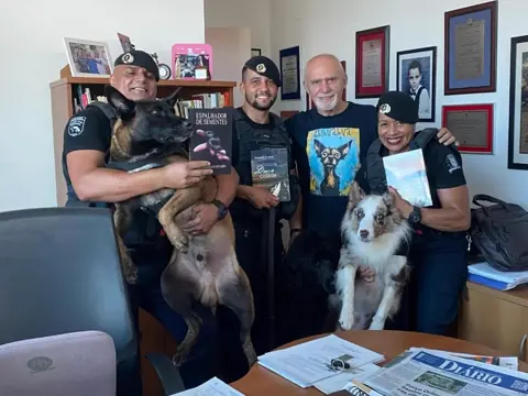 Benedito Furtado com agentes do Canil da Guarda Civil, cães e exemplares de seus livros.