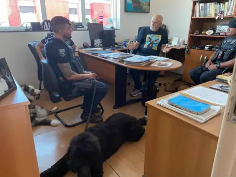 Benedito Furtado conversa com agentes do Canil da Guarda Civil em seu gabinete, acompanhado por cães.